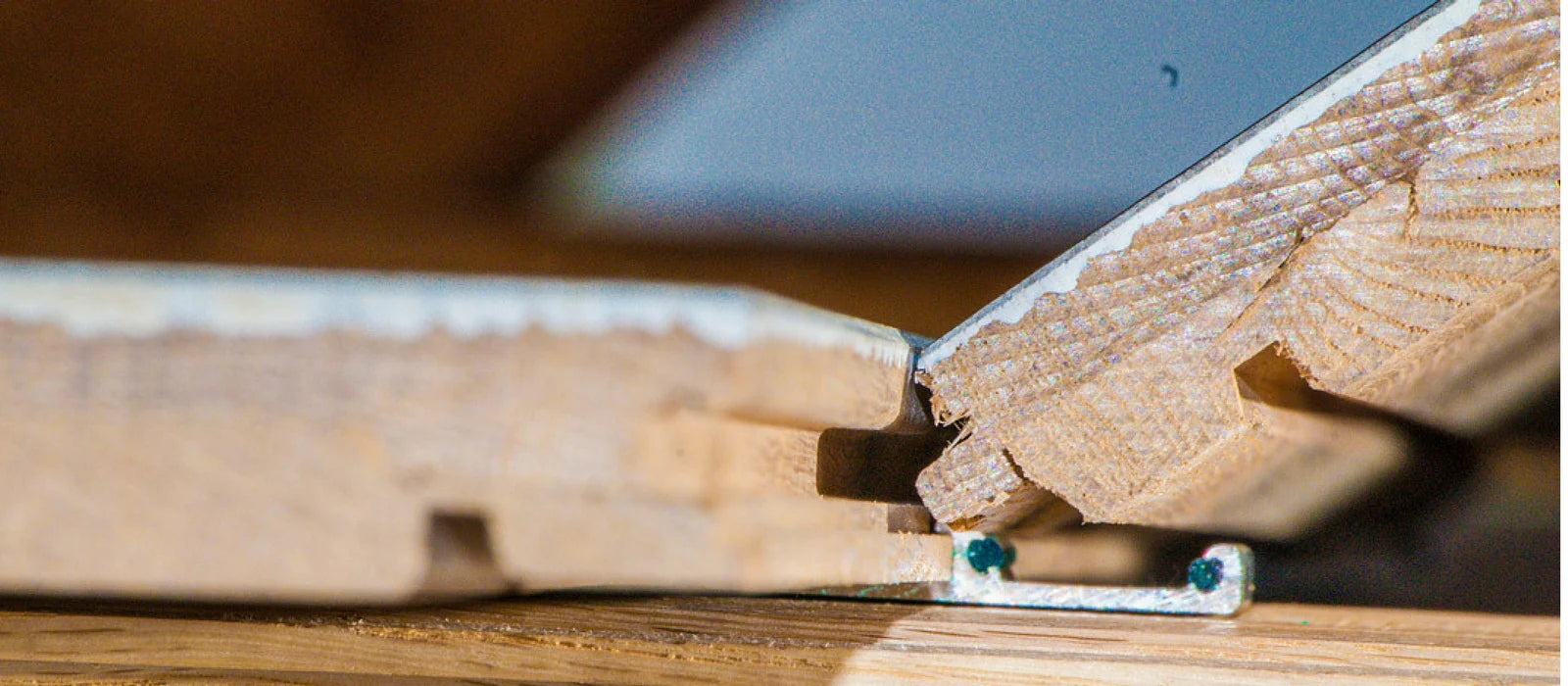 Close-up view of Easiklip hardwood flooring installation, showing the aluminum clip system securing the tongue-and-groove planks for a seamless floating floor setup.