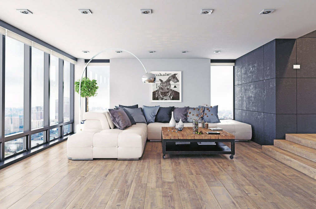 Spacious modern living room with floor-to-ceiling windows, a white sectional sofa, and rustic hardwood flooring. The open-concept design combines contemporary decor with warm wood textures.