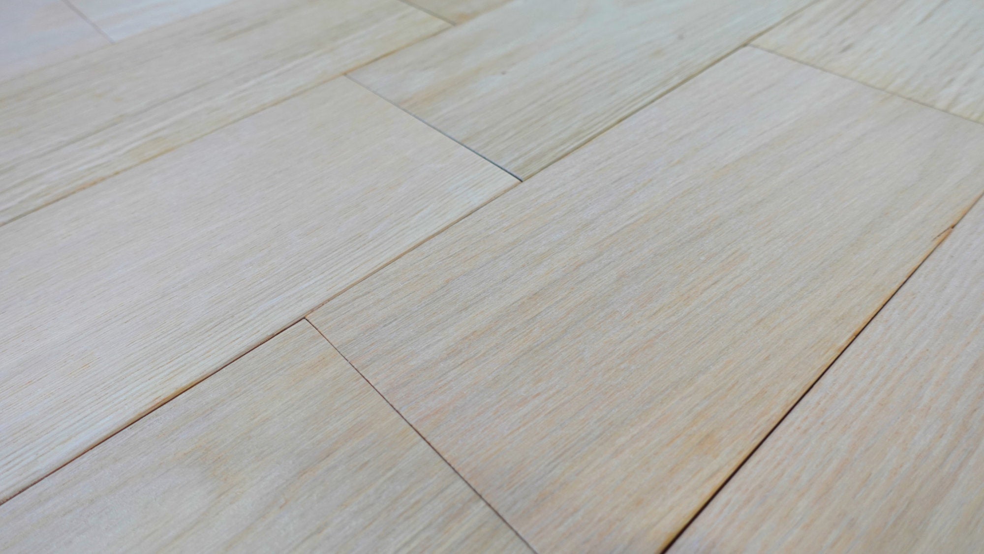 Close-up of Nexus Unfinished 5" White Oak Solid Hardwood flooring with rectangular planks in a parallel layout, featuring a smooth, natural texture and beveled edges. Compatible with radiant heat for enhanced comfort.